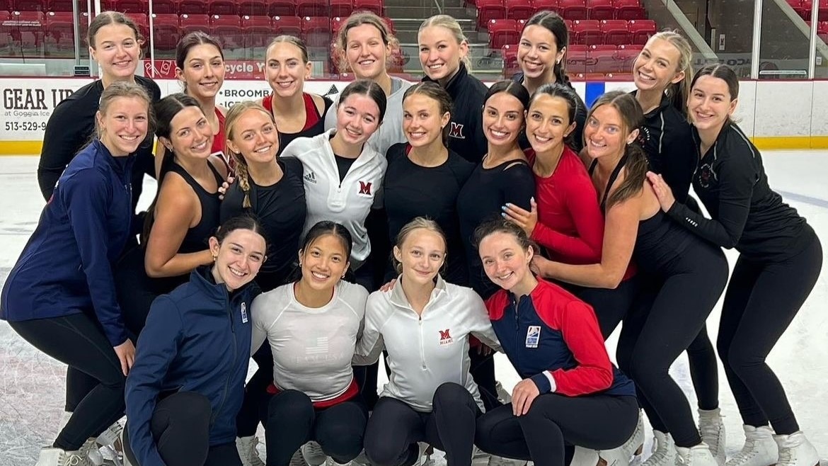 Miami University, made up of 20 skaters, poses for a photo on the ice. They're all smiling, split into three rows, the bottom row kneeling, the middle row crouching and the top row standing.