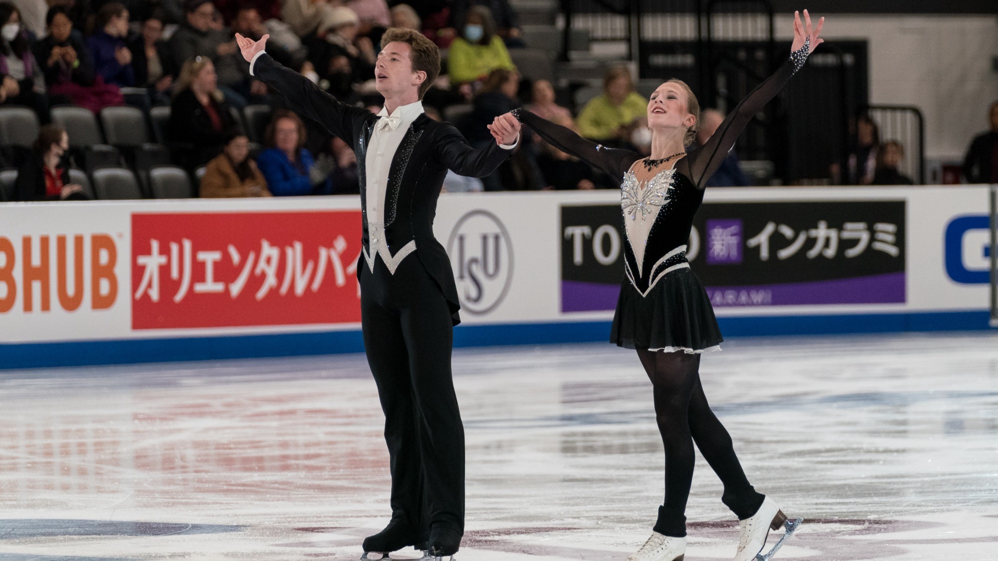 Maria Mokhova and Ivan Mokhov salute to the crowd after their performance. Both wear black and white, his outfit mimics a tux while her dress is black with white down the front.