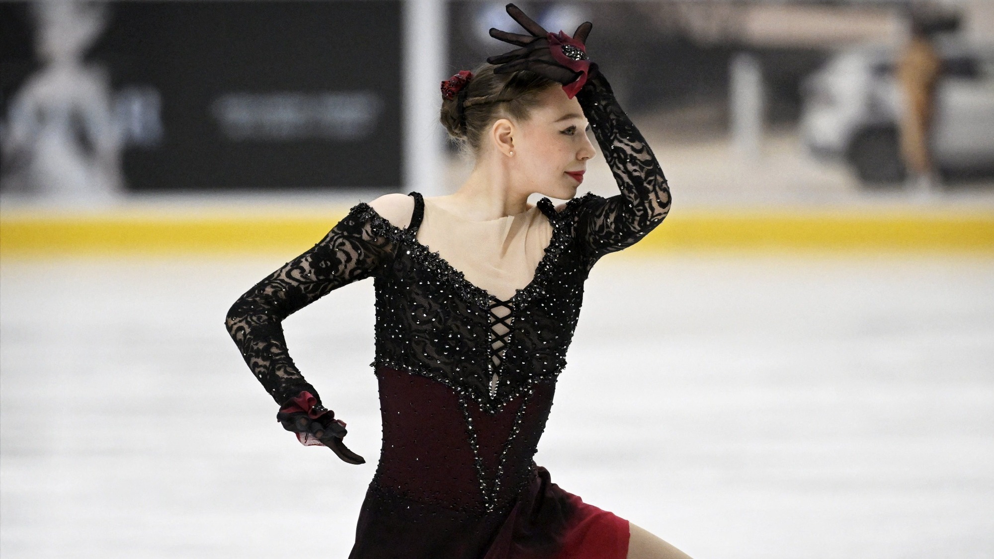 Shot from the waist up, Lindsay Thorngren, wearing a very classic Spanish tango style dress that is red and black with lace and her hair in a bun, looks to the right, her arm curving up an around her head.