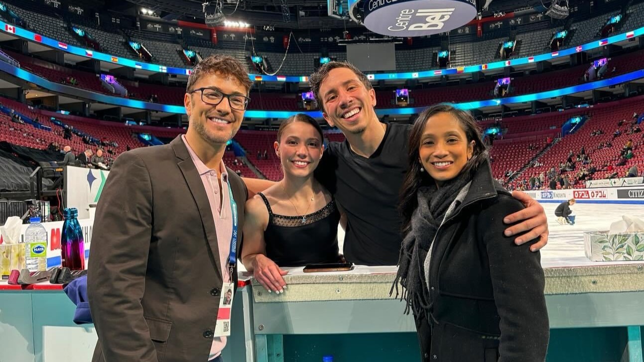 Valentina Plazas and Maximiliano Fernandez stand at the boards, their arms wrapped about their coaches (Jim Peterson left) and Amanada Evora Will (right). They all smile, the rink in the background.