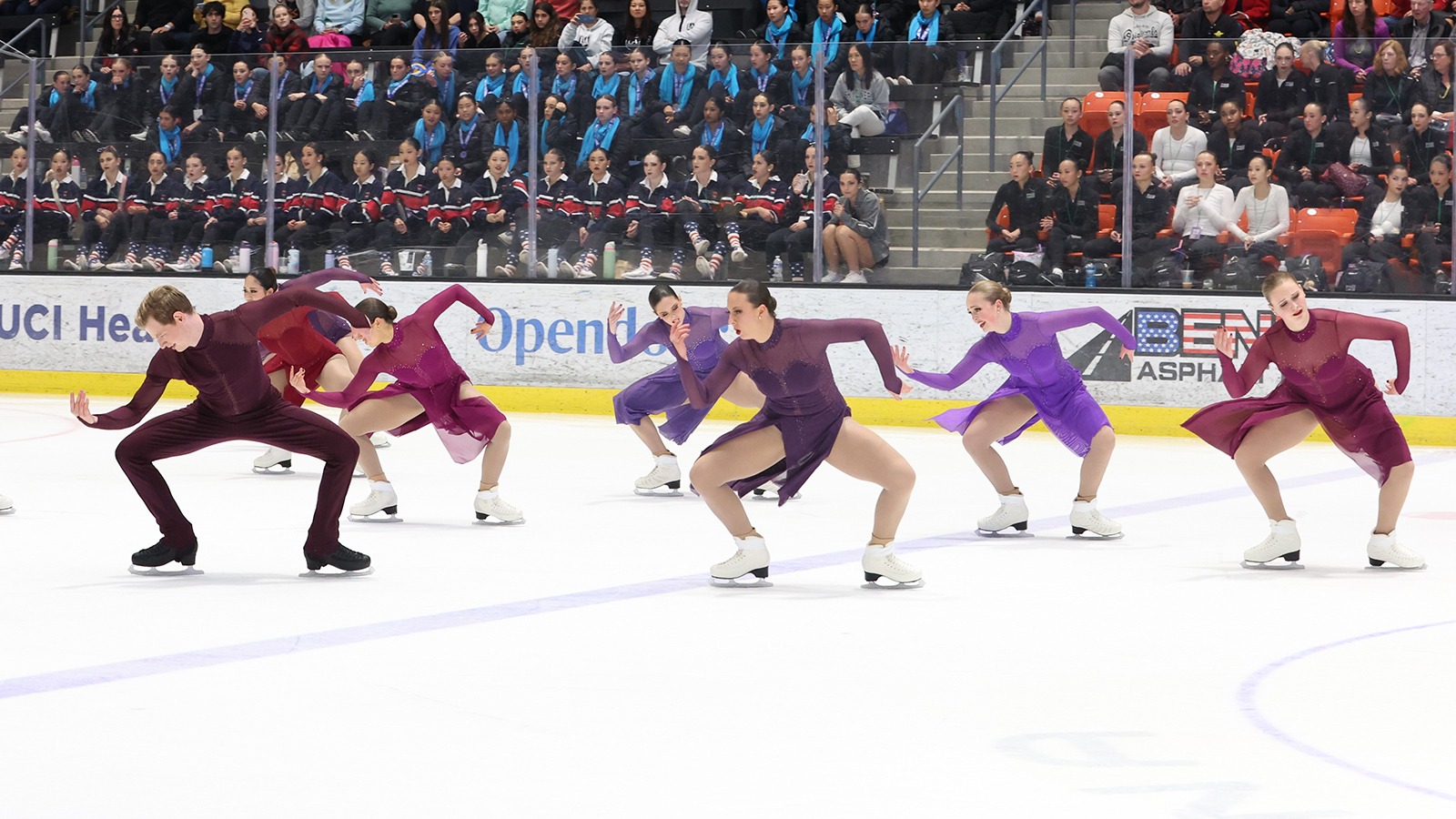 The Haydenettes perform their free skate wearing coordinating purple and maroon skating costumes. They all bend over to the left with their arms making an 