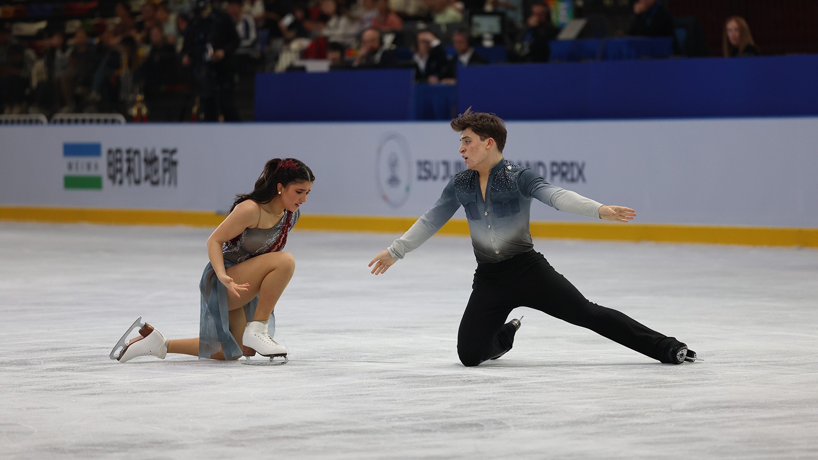 Dressed in different shades of gray, Elliana Peal and Ethan Peal are on one knee, facing each other, during their 