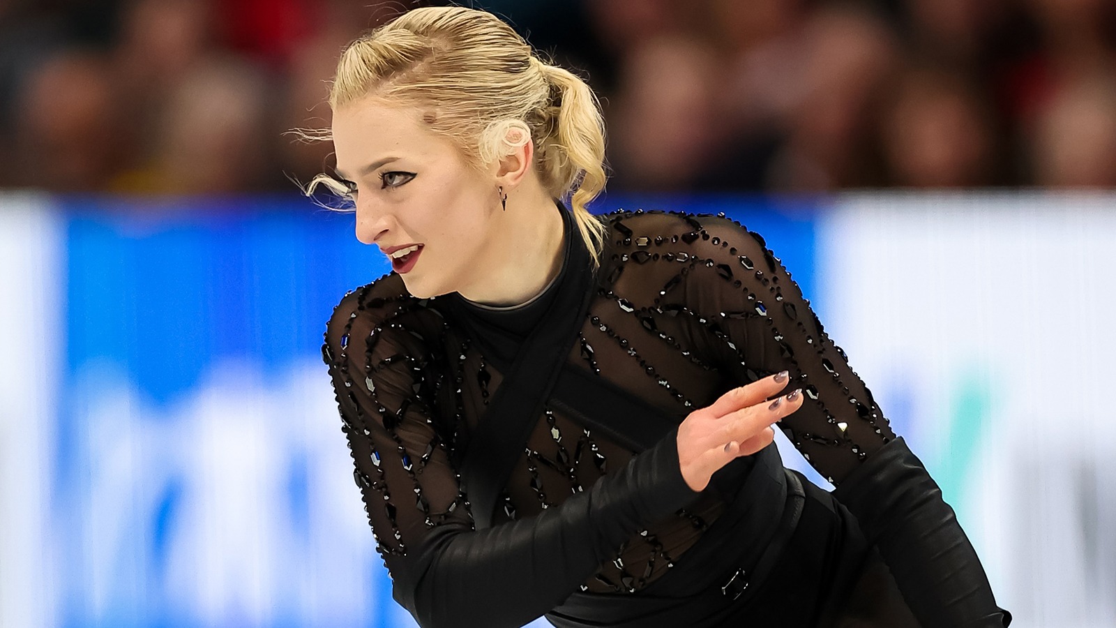 Amber Glenn, wearing a beaded black costume, looks to the side in a close-up competition photograph.