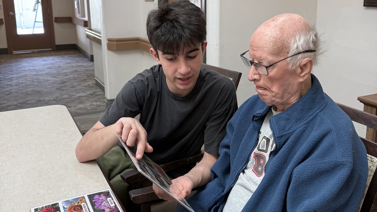 Ryan Azadpour sits next to his grandfather, who has Alzheimer's disease, and points to pictures in a book. 