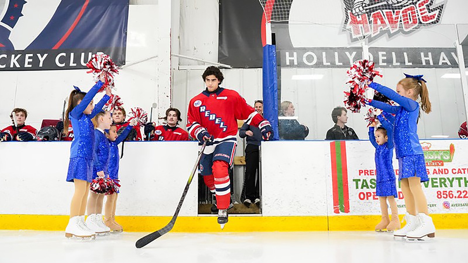 The Twisted Toepicks, dressed in blue, cheer on the Philadelphia Rebels, dressed in red, as they take the ice for their hockey game.