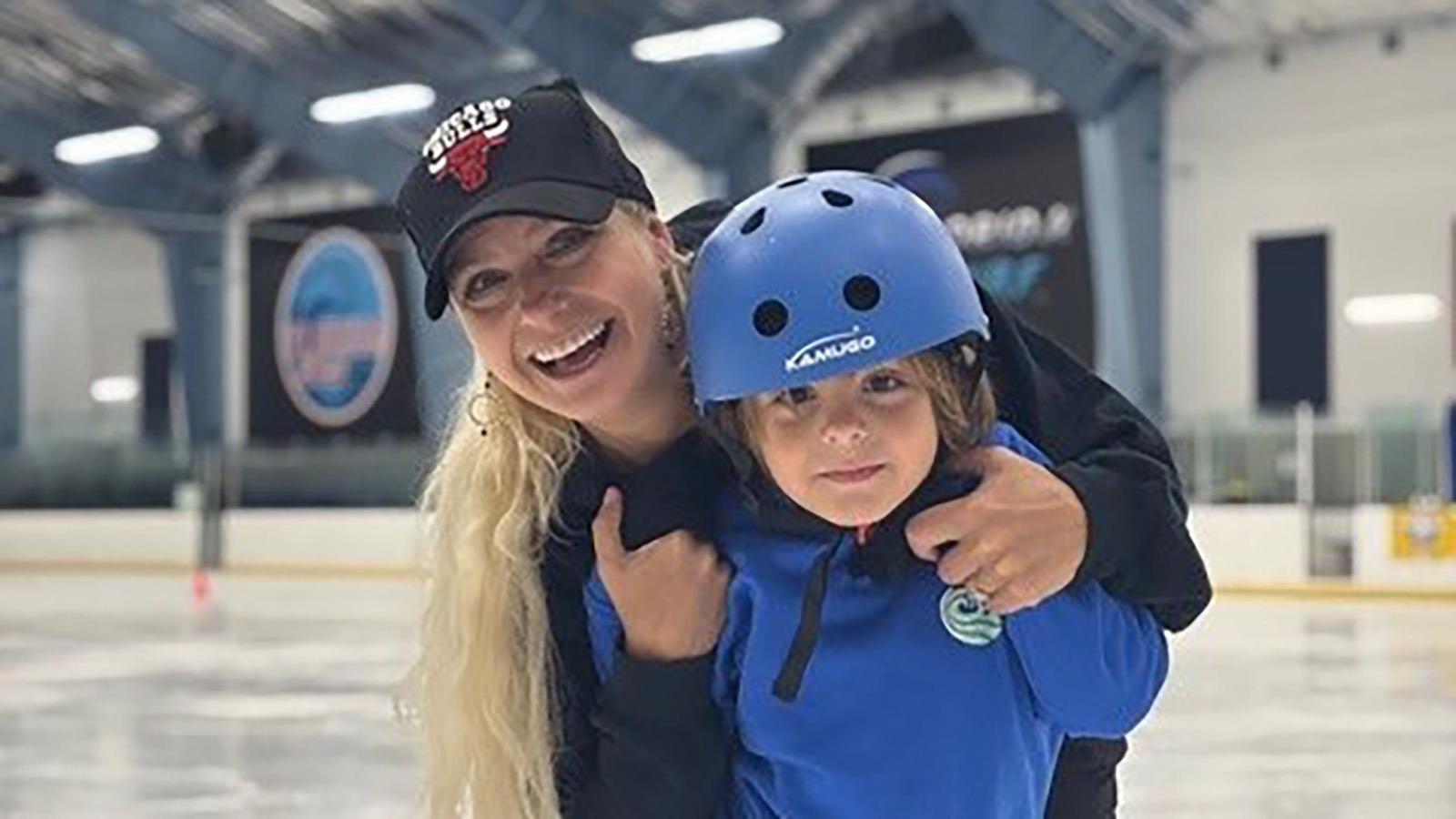 Nicole Bobek and son on the ice. She's wearing a Chicago bulls cap and he's wearing all blue, including a helmet.