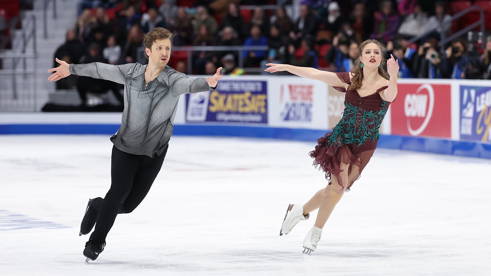 Anthony Ponomarenko  and Christina Carreira skate side by side, arms extended in front and back, in unison.