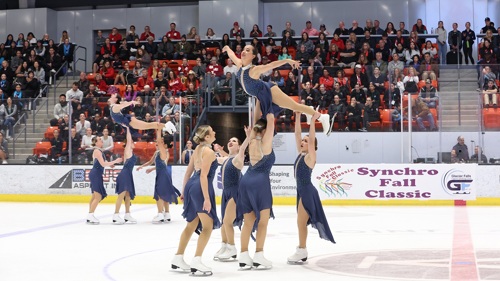 Two groups of Skyliners hold up a fellow skater during a lift element.