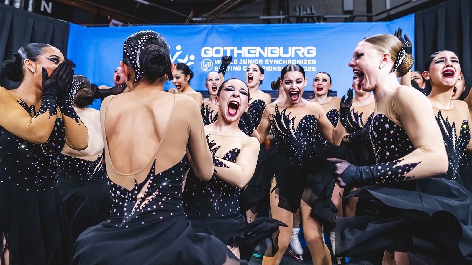 Dressed in black, Teams Elite celebrates its historic World title in the kiss and cry.