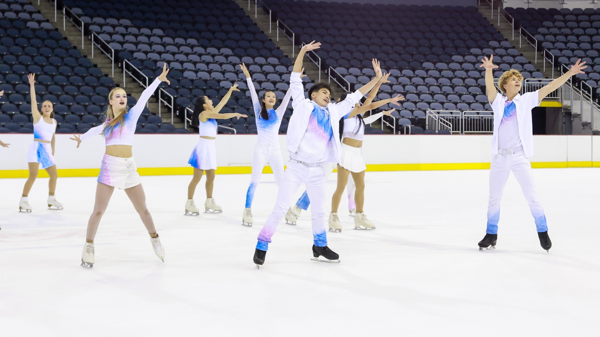 Act 1 of Boston performs wearing matching blue and white costumes. They all stand with their arms in the air