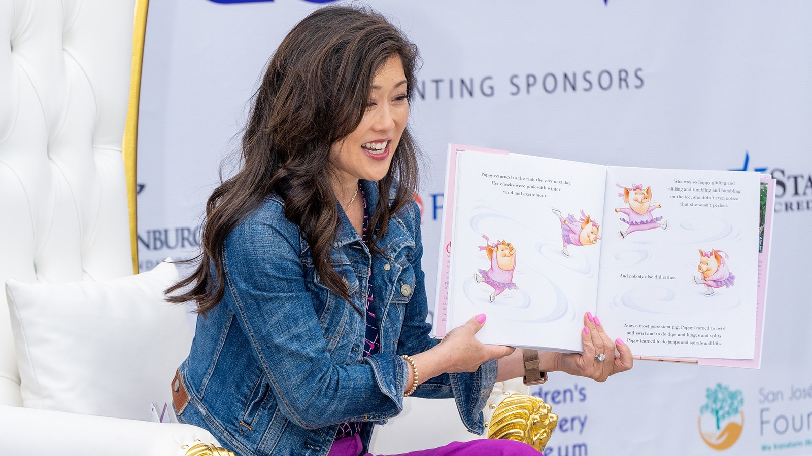 Kristi Yamaguchi holds a book open while reading to young students.