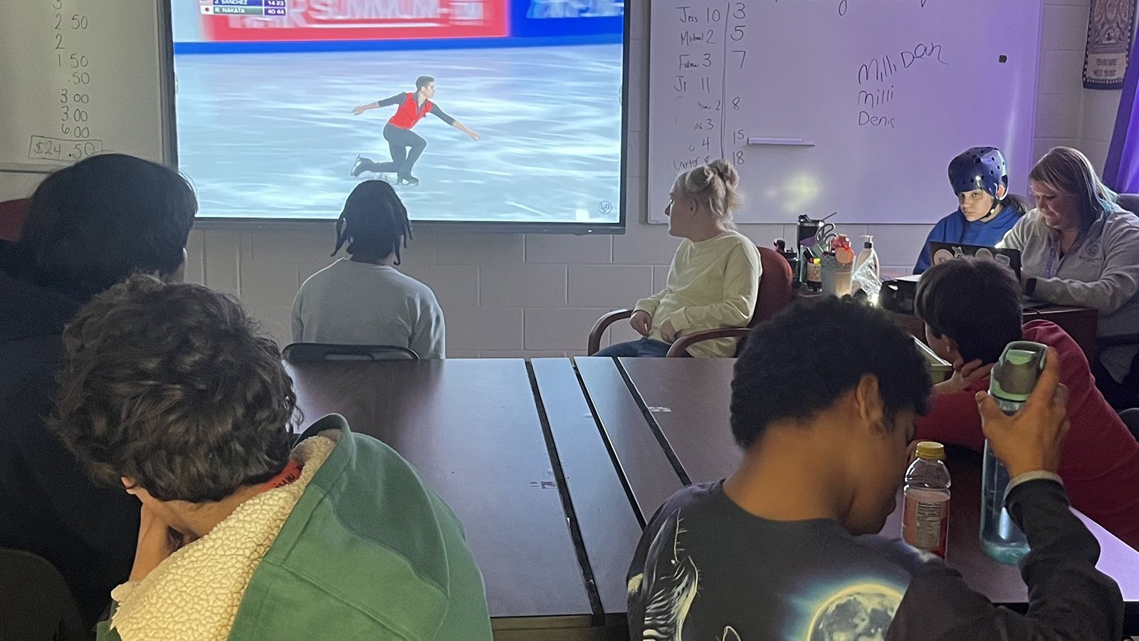 Students in a classroom watch Jacob Sanchez skate on a big screen