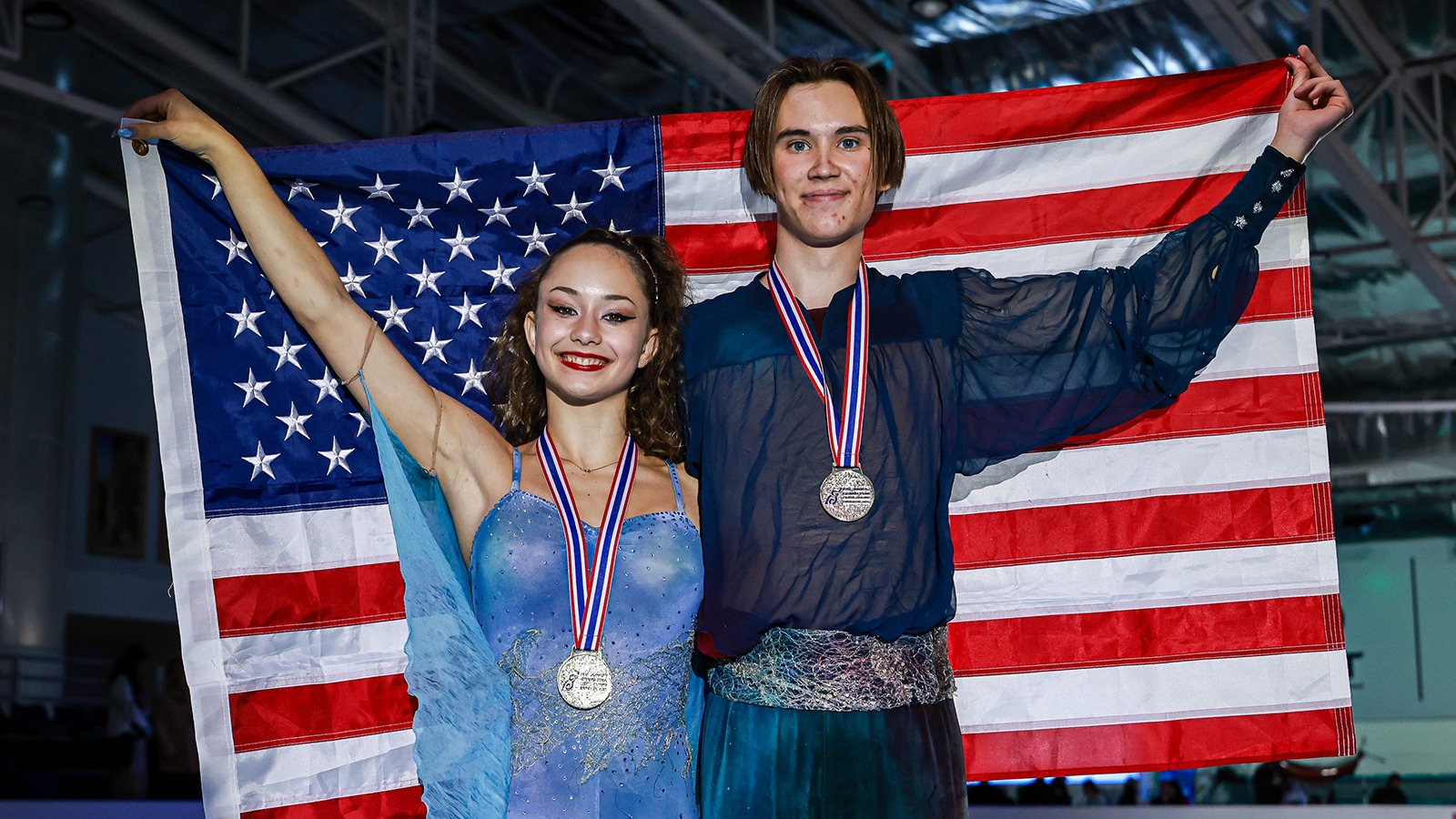 Hana Maria Aboian and Daniil Veselukhin hold up the American flag after receiving their gold medals at Junior Grand Prix Thailand