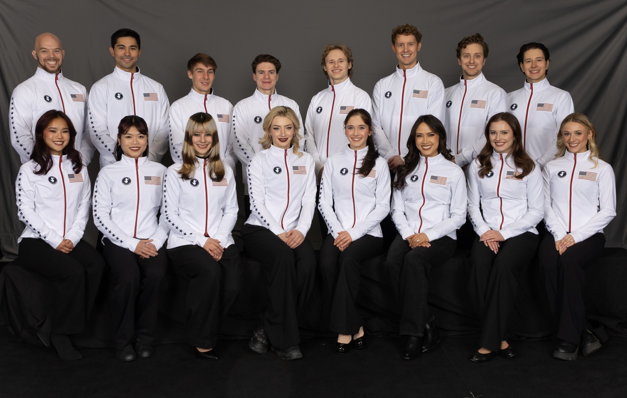 The 2026 U.S. Olympic Team poses with an official photo in matching white jackets and black pants against a dark backdrop