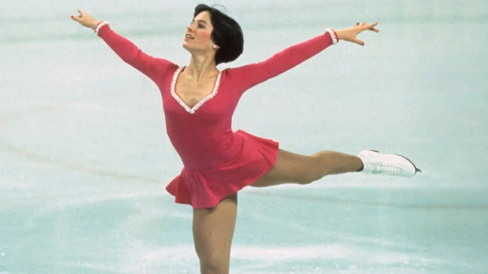 Wearing a red dress with white trim, Dorothy Hamill displays her elegance and grace in her Olympic free skate.