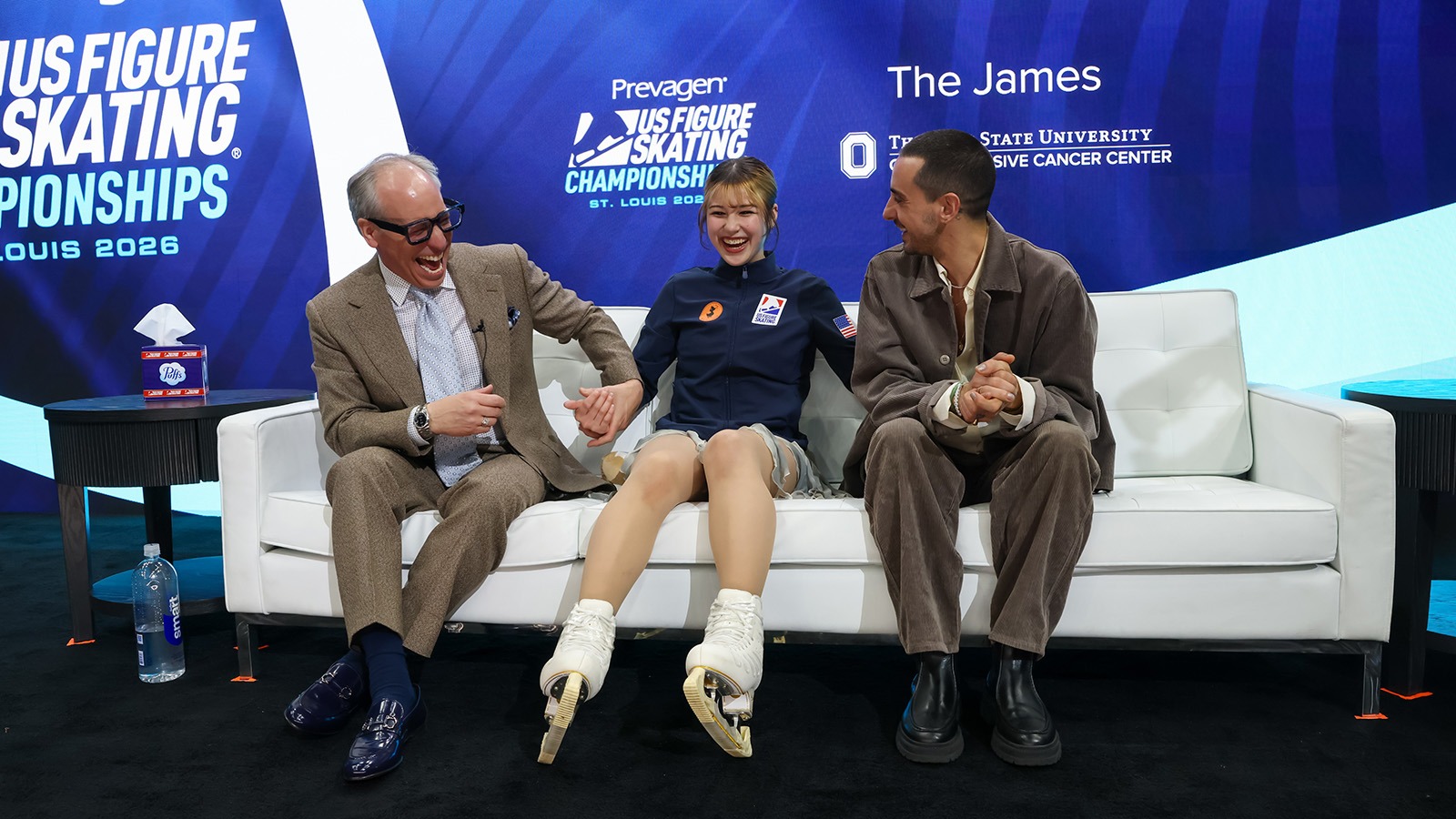 Alysa Liu, laughing, has some fun in the kiss and cry with coached Phillip DiGuglielmo and Massimo Scali in St. Louis