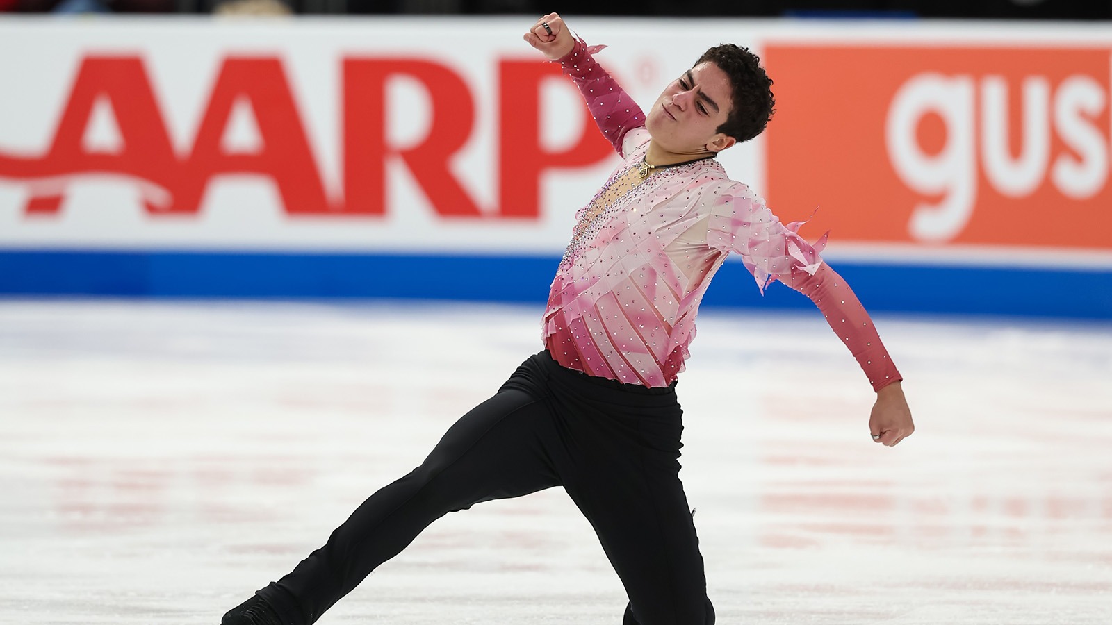 Dressed in pink, Jacob Sanchez throws down his short program with a fist in the air. 