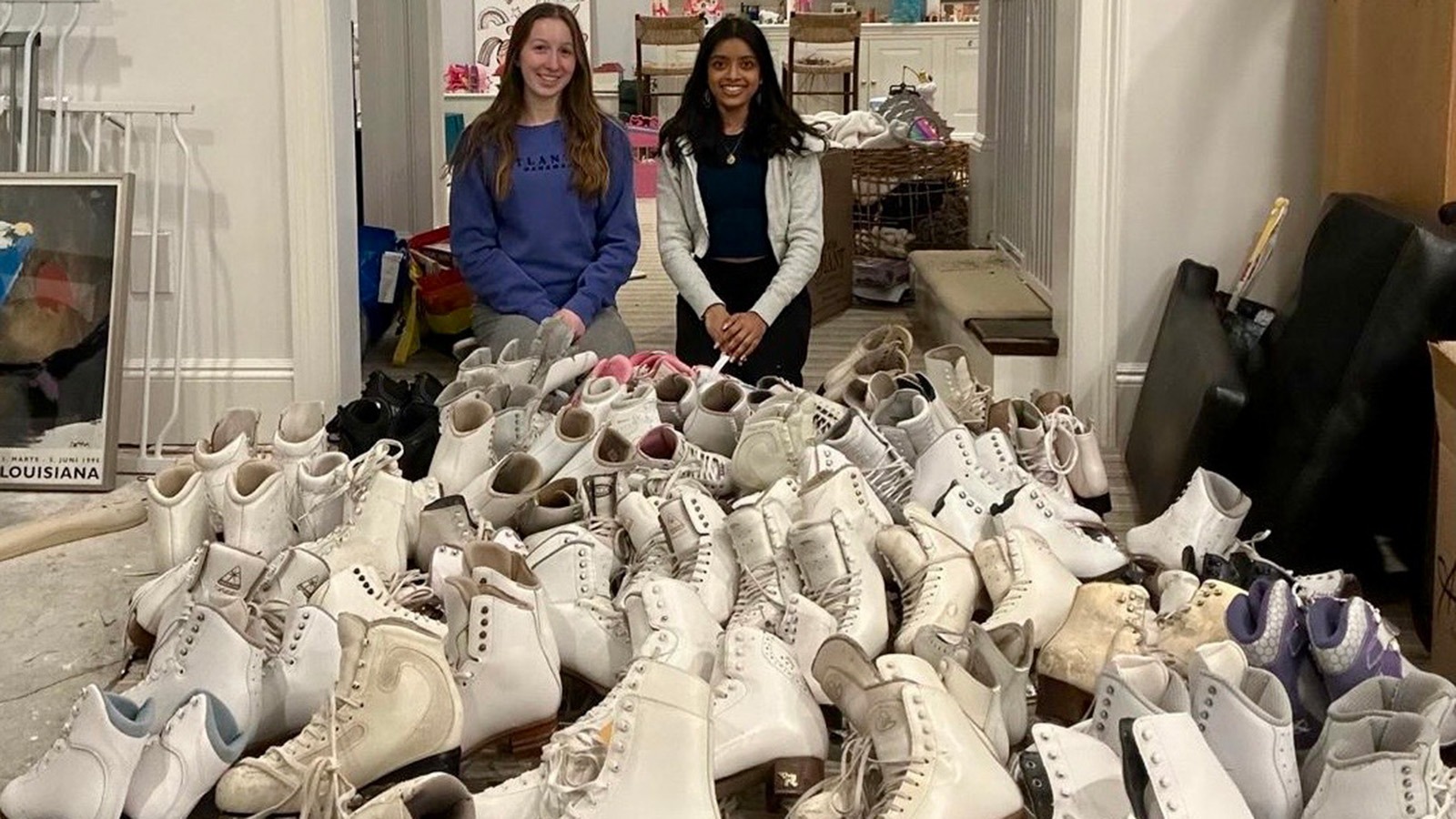 Kaja Laybourn and Tanya Jay stand behind a huge pile of skates, which they plan to donate or repurpose.
