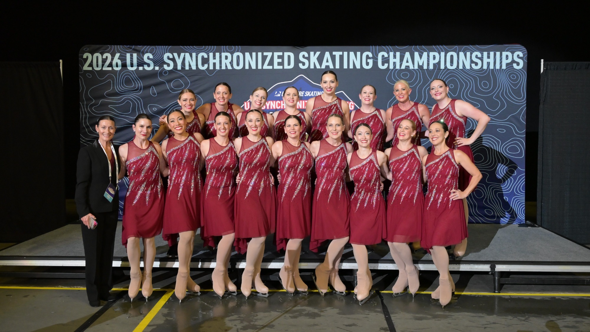 Ice Denettes Tenacity, wearing purple, stand in the kiss and cry at the 2026 U.S. Synchronized Skating Championships.