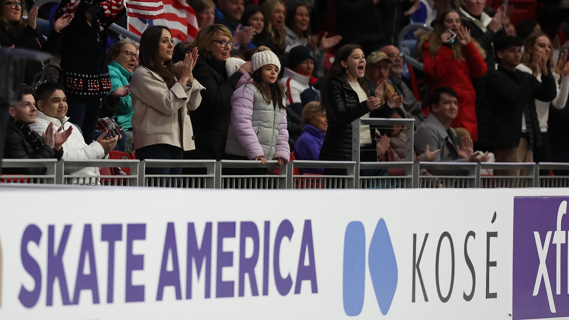 Fans cheer in the stands. Some hold up American flags of varying sizes