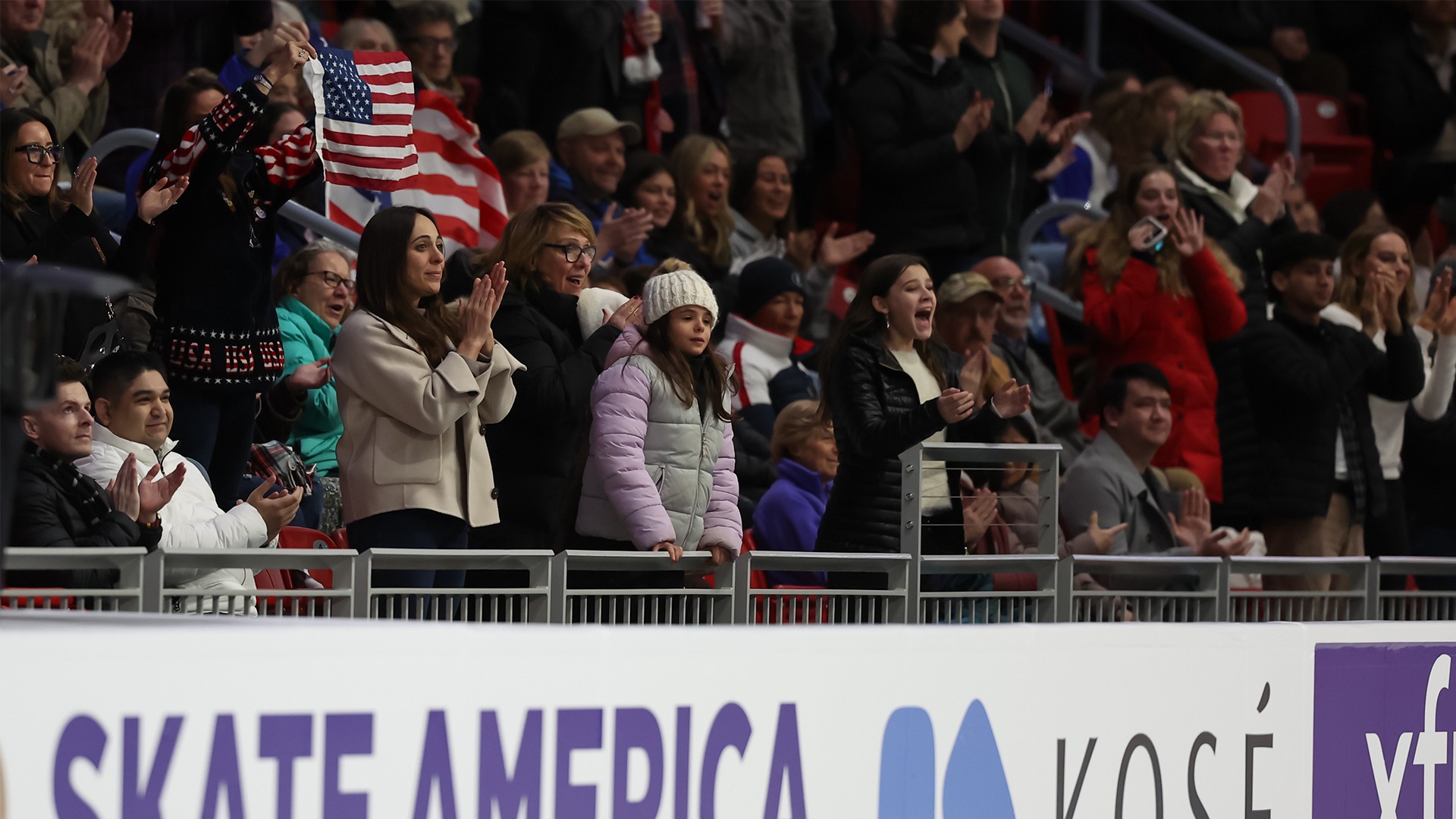 Fans cheer in the stands. Some hold up American flags of varying sizes