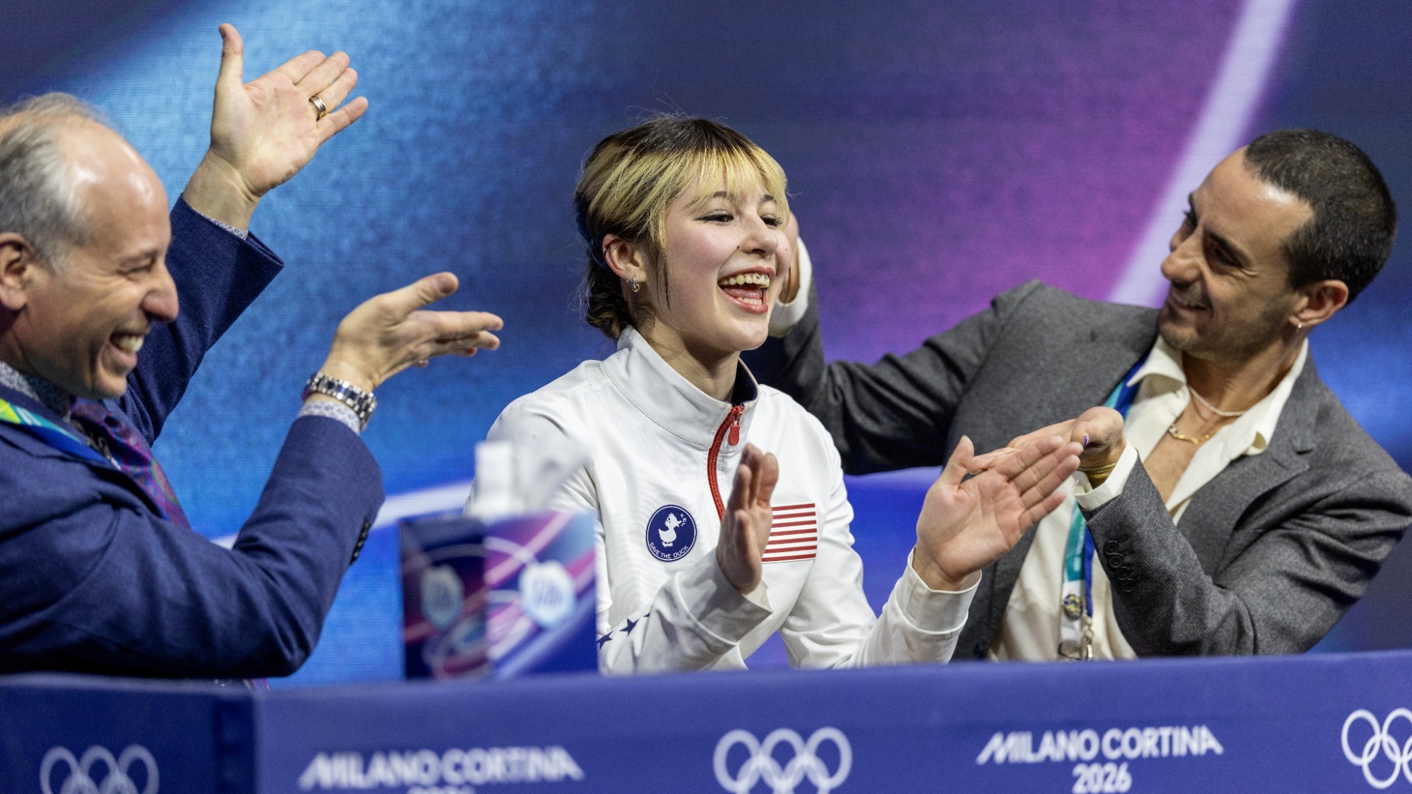 Alysa Liu and her coaches Phillip DiGuglielmo, left, and Massimo Scali celebrate the skater's scores at the Olympics.