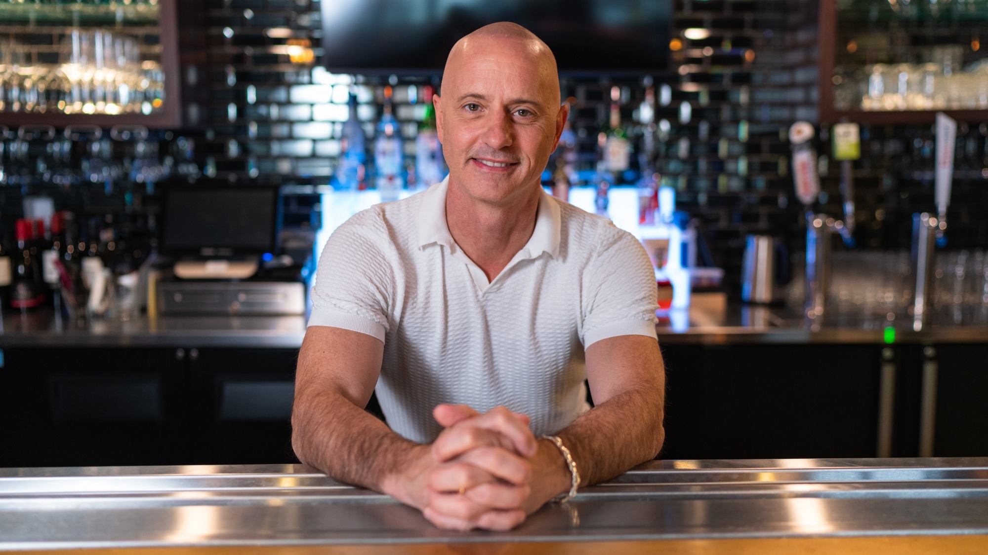 Olympic champion Brian Boitano, pictured wearing a white t-shirt, standing ready to tend bar
