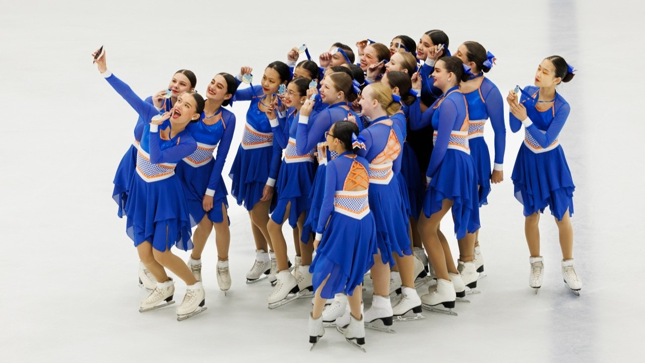 Boston Fusion's juvenile team, dressed in blue, takes a selfie after performing their Space Jam routine at the 2026 U.S. Synchronized Skating Championships. 