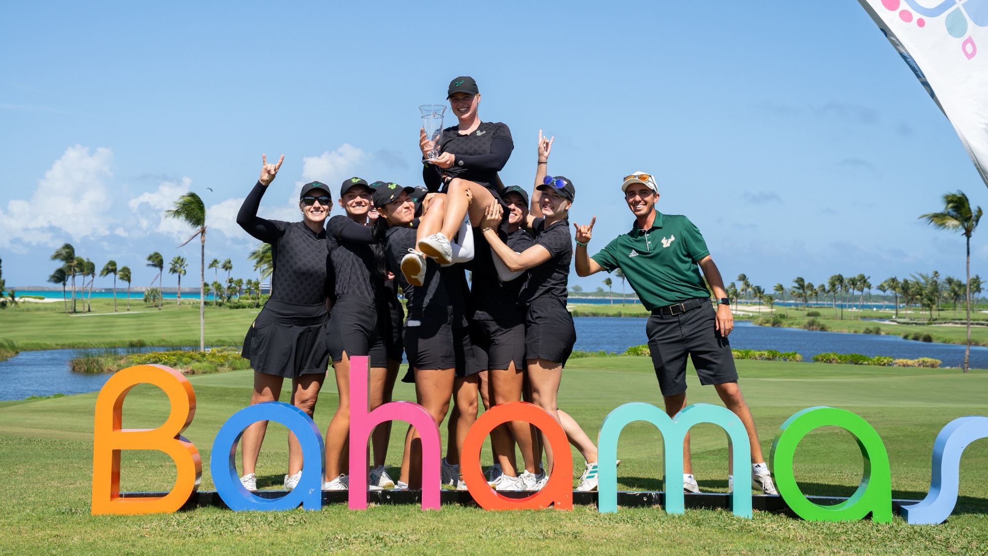 The Women's Golf team holds up Cherry Marley in celebration of her individual championship.