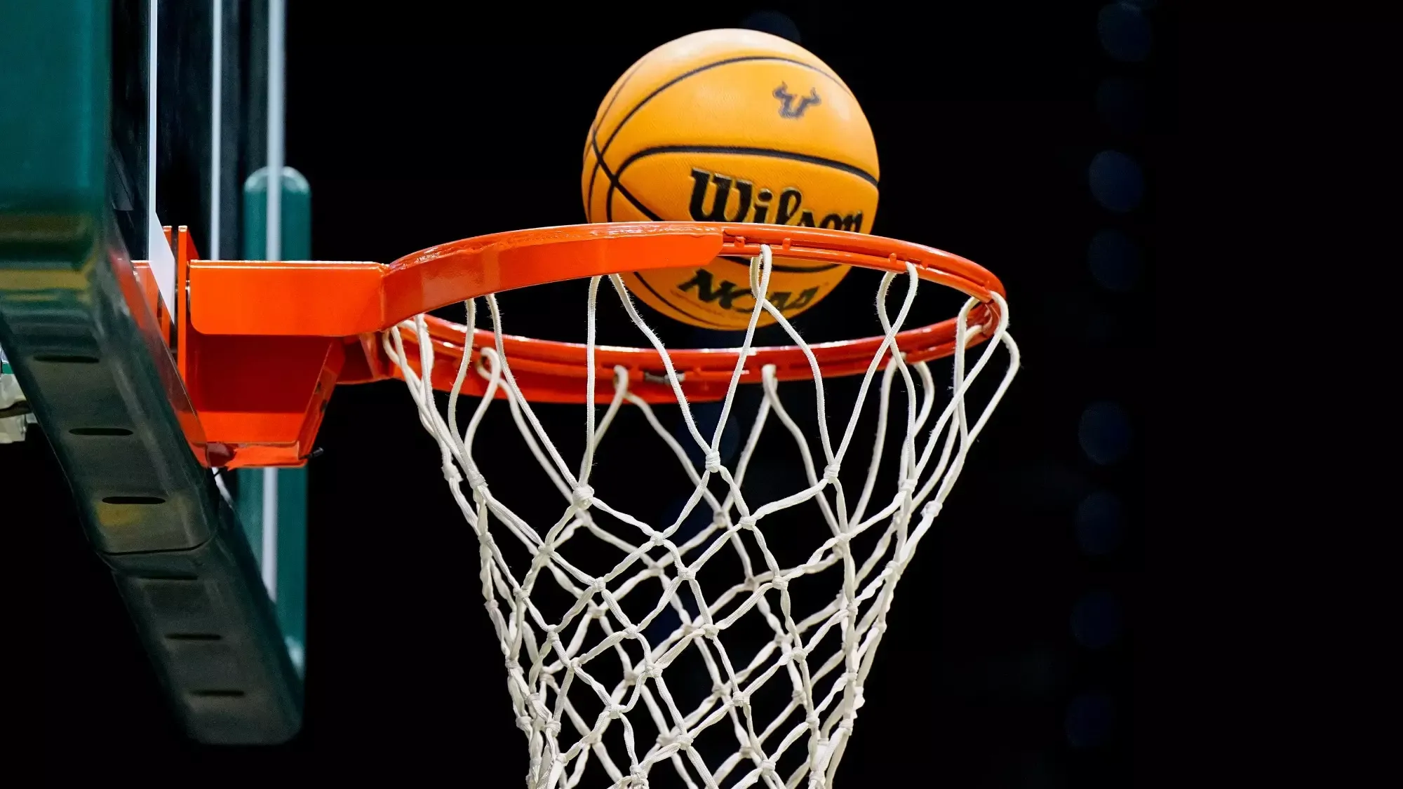 Photo of a basketball going in to a hoop.