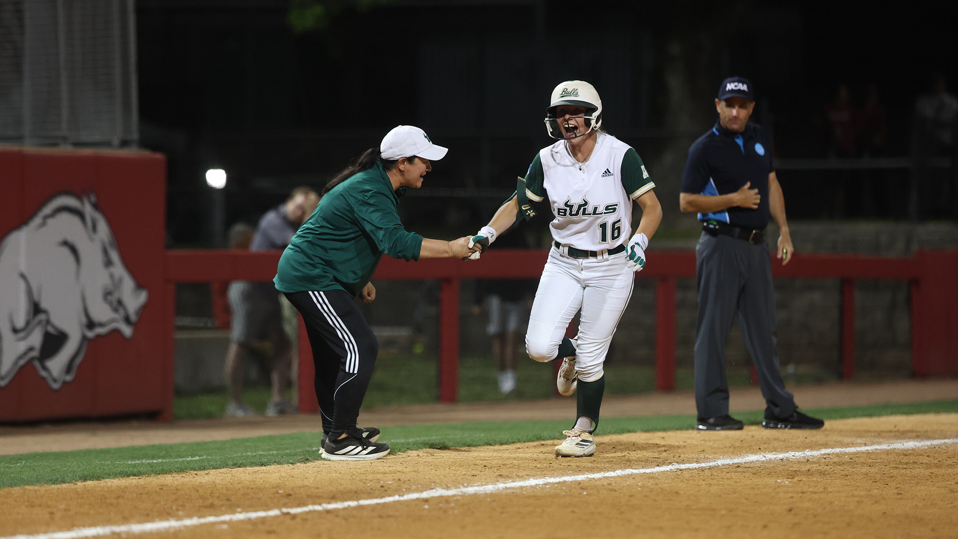 Olivia Elliott rounding third and celebrating with Coach Navas after tying the game with a solo home run