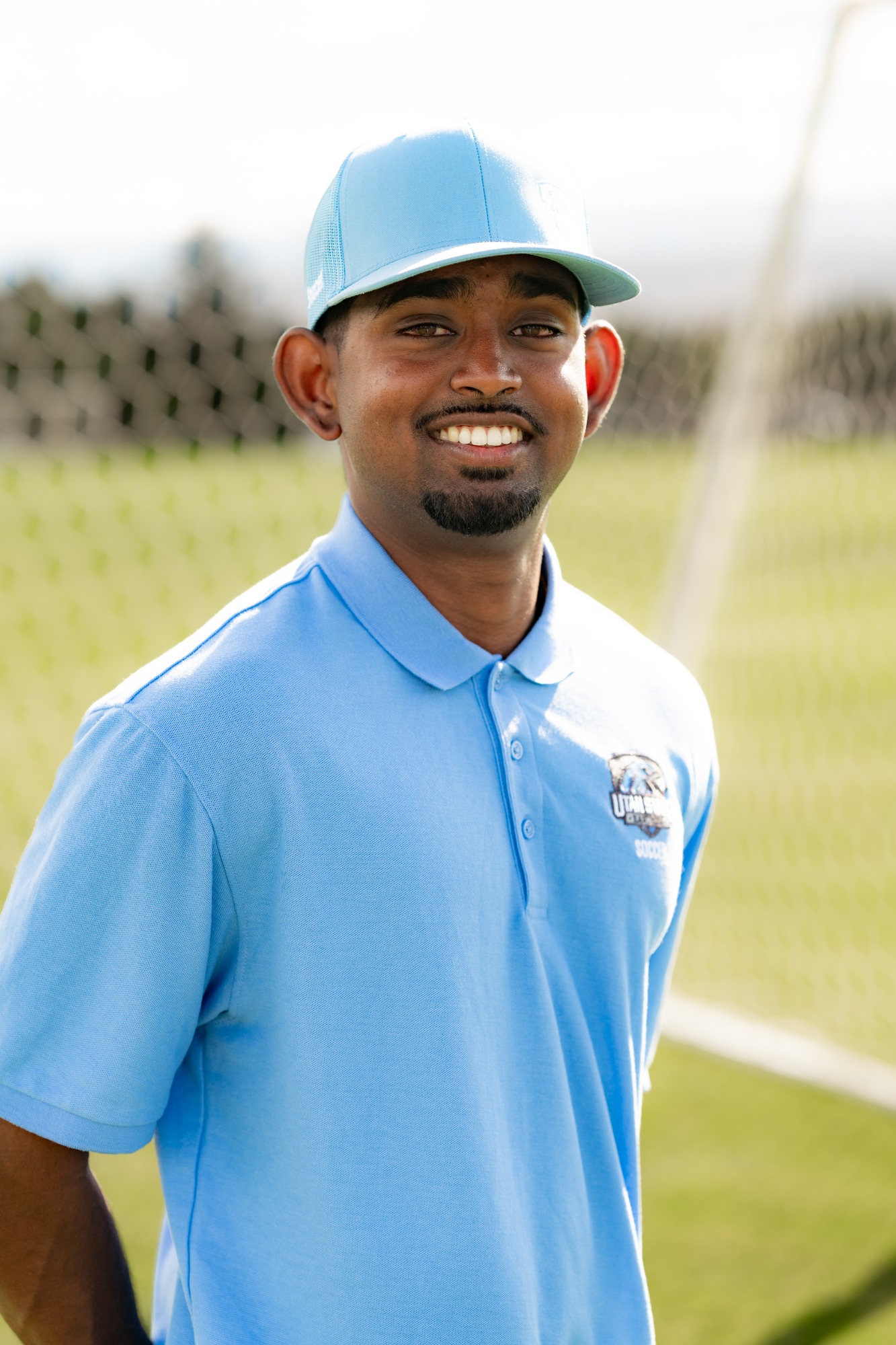 Utah State Eastern men’s soccer staff member wearing a light blue Utah State Eastern polo and cap, smiling for a headshot on the soccer field