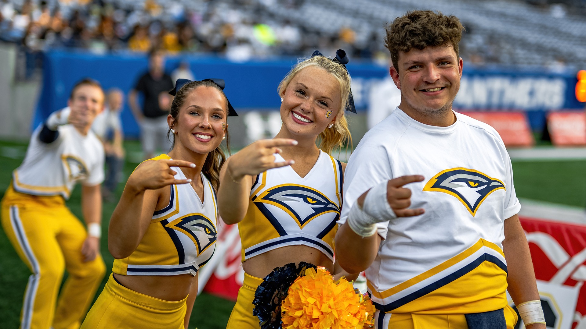 Cheerleaders flash the Power C hand sign on the sidelines of the Georgia State football game