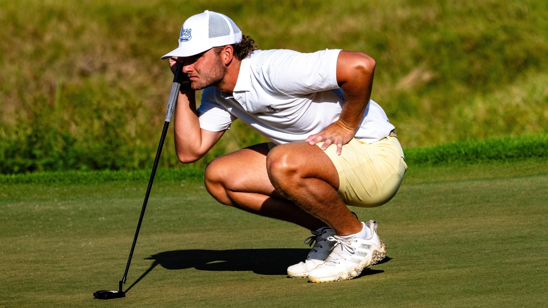 Ward Harris reads the green crouched behind his marker at the Honors Course