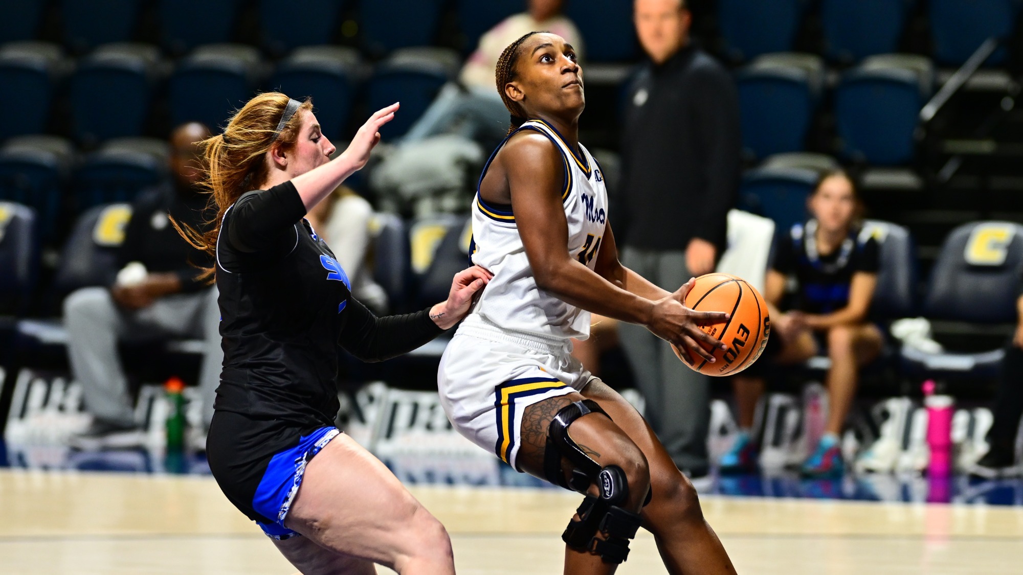 women's basketball player preparing to shoot basketball with opponent behind her.