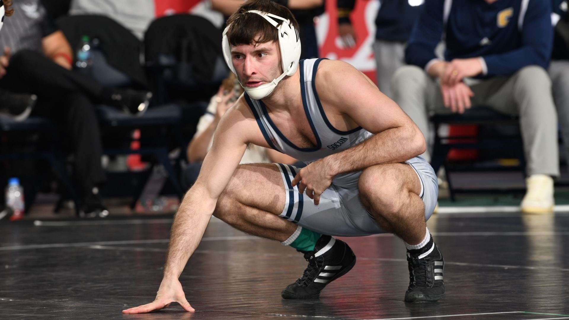 Cooper Flynn crouches with his hand on the mat studying his opponent.