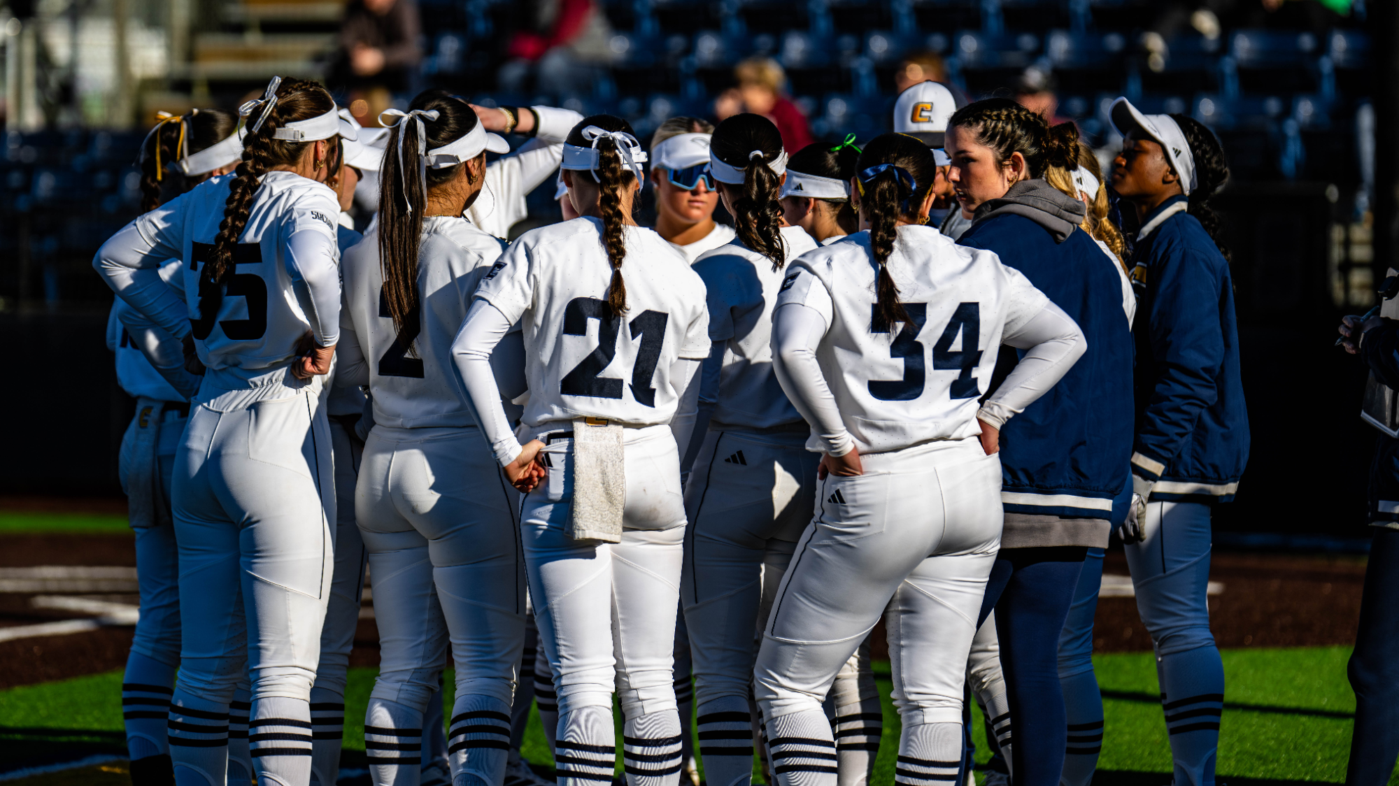 An softball team huddled up on the field before a game.