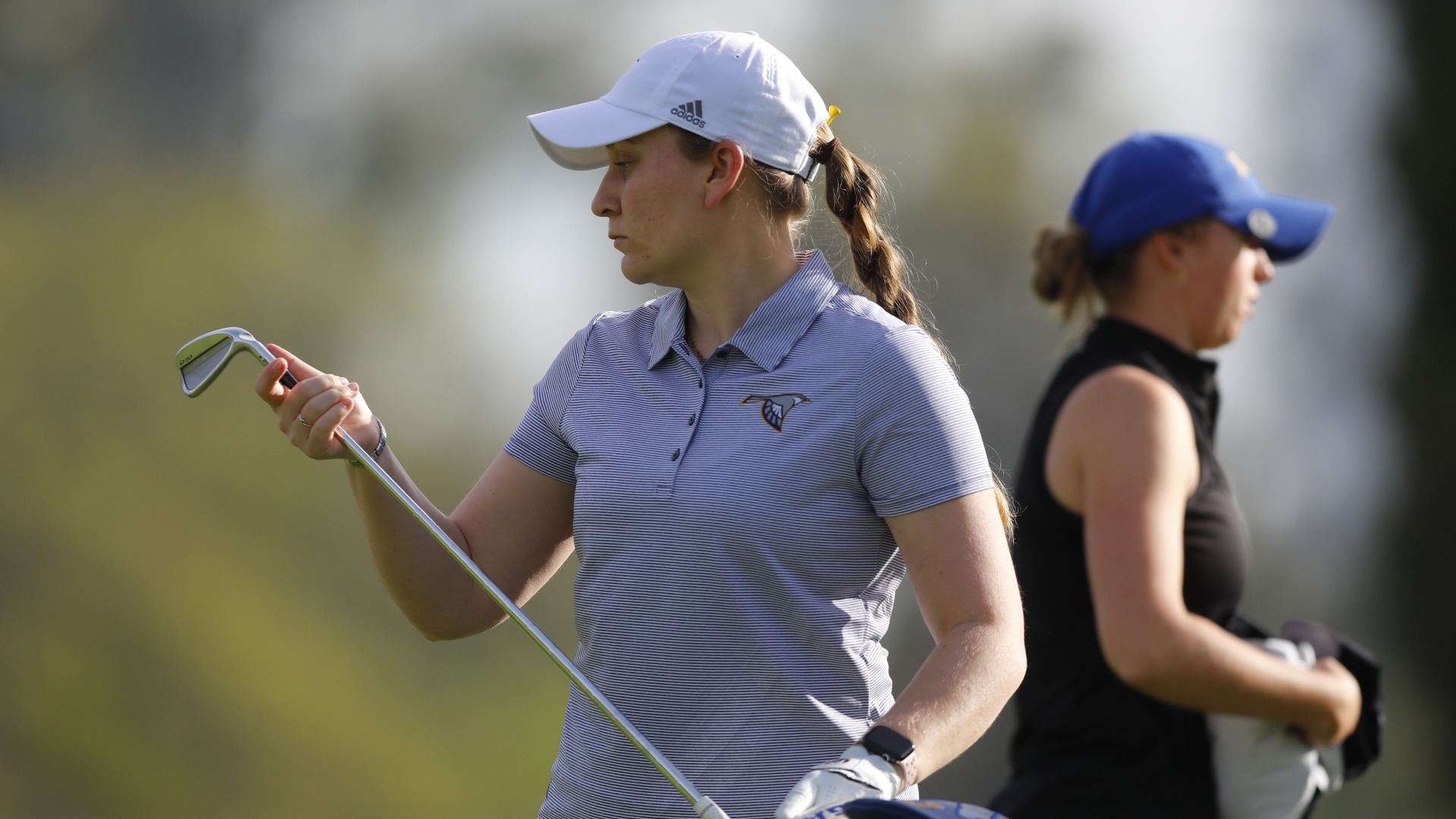 Makenzie Cooper stares at her club head as she takes the iron from her bag