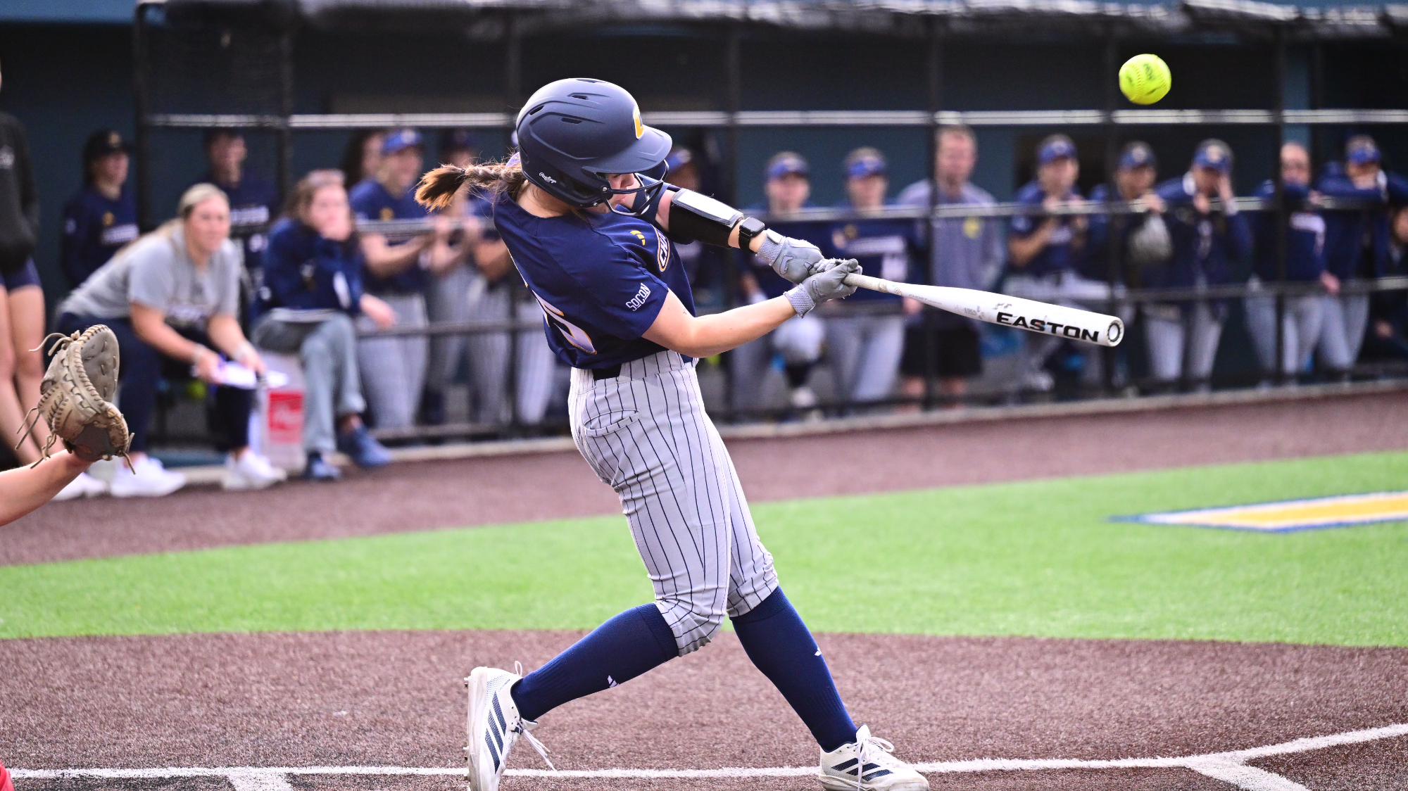 Softball player at the plate hitting the ball.