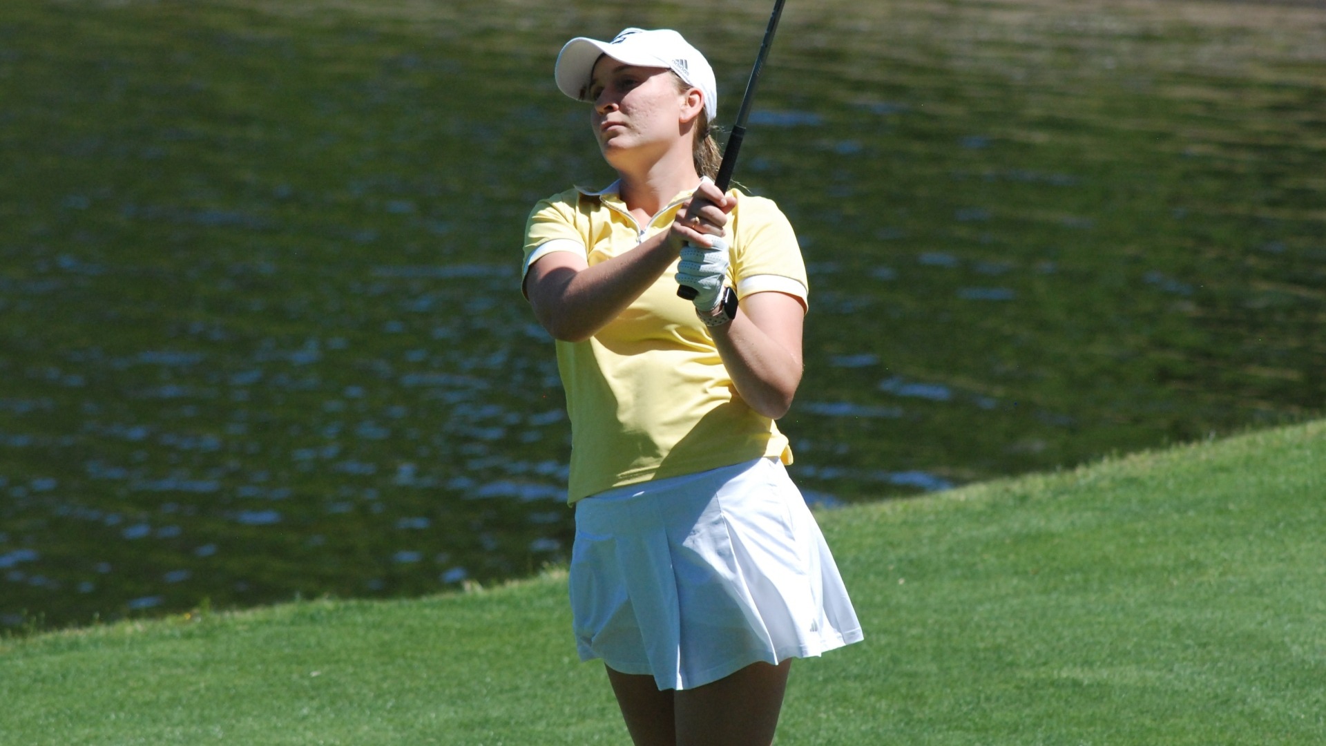 Makenzie Cooper watches her tee shot with a serene lake in the background at the 2025 SoCon Championships