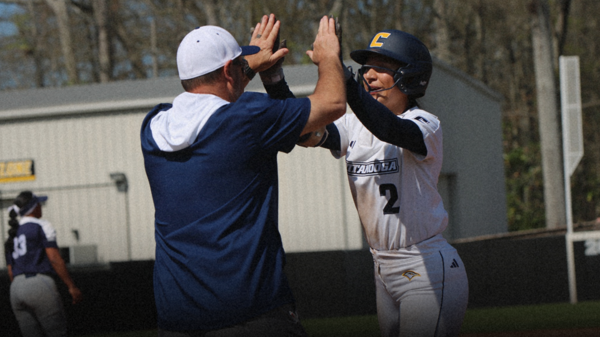 A softball player high fives her coach after reaching first base.