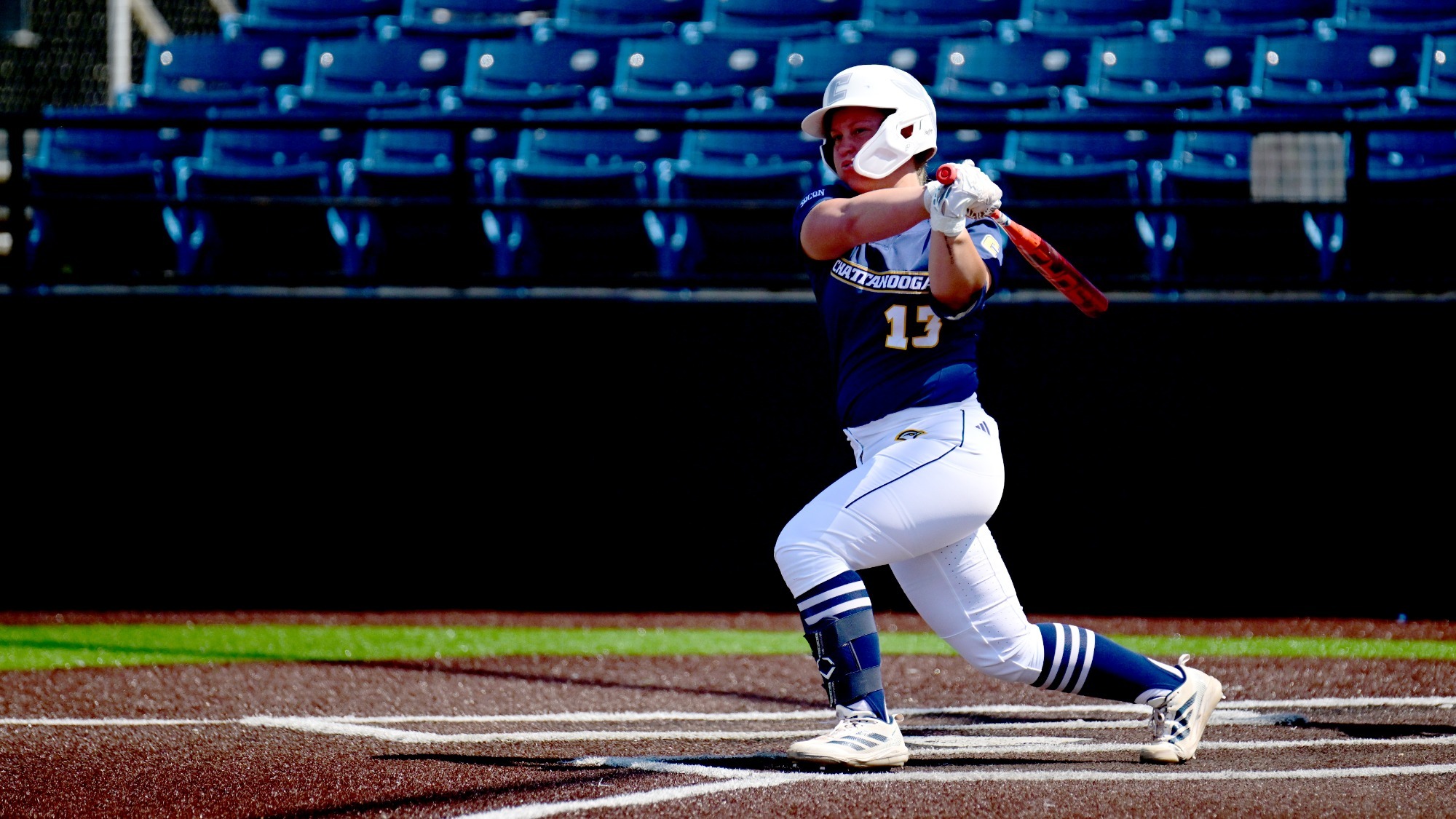 A Chattanooga softball player at home plate hits the ball.