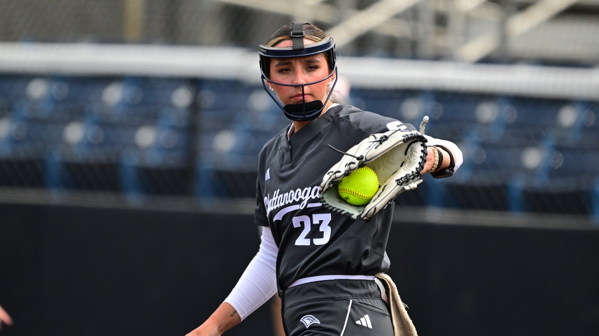 A softball pitcher catches the ball thrown back by the catcher.