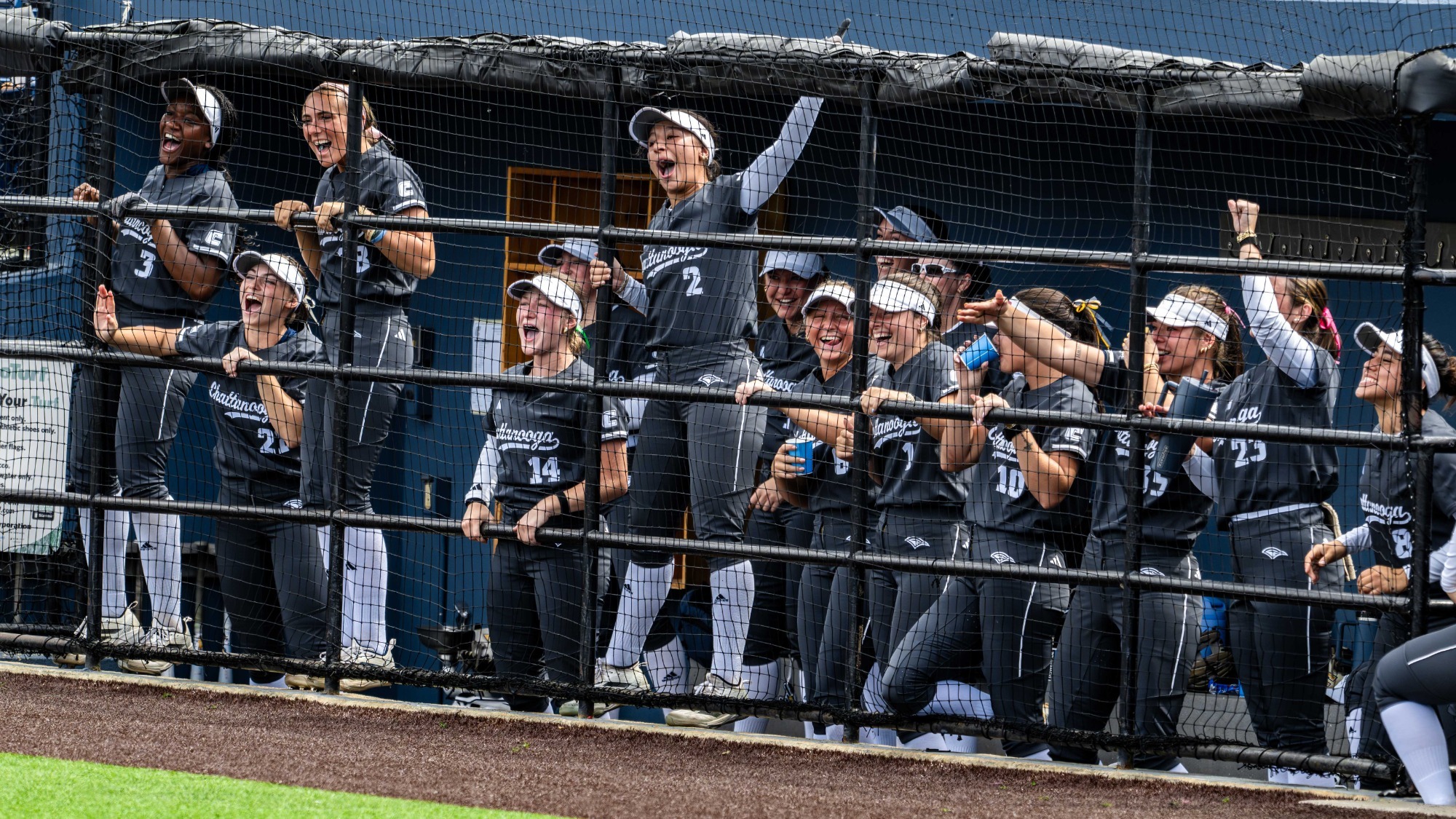 Softball team is cheering in the dugout after a teammate hit a home run.