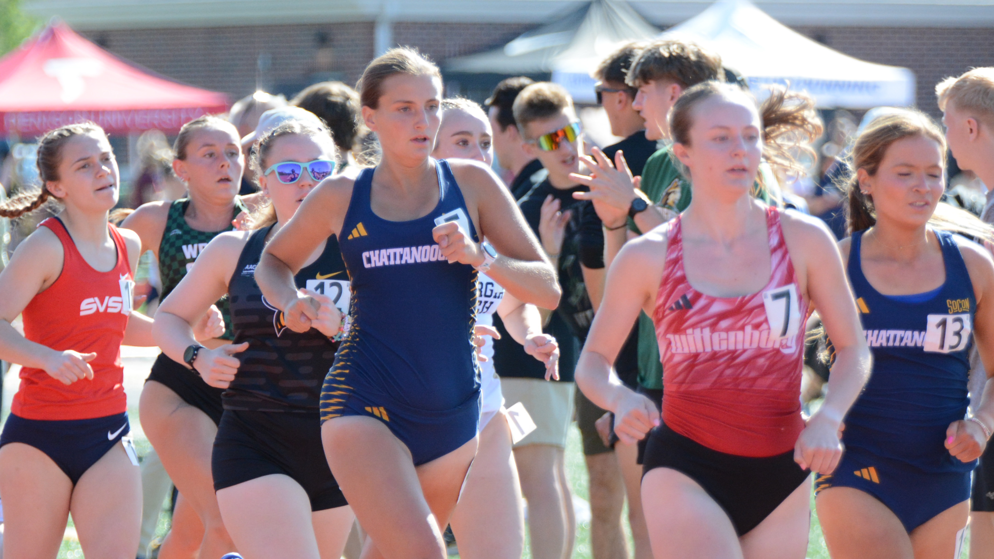 Several runners on the track racing on a sunny day in the 1500 meter run.