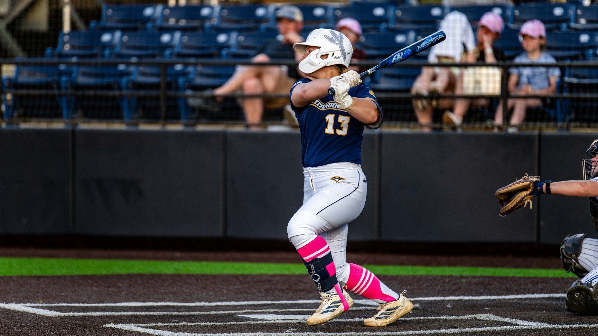A softball player gets a hit during a game.