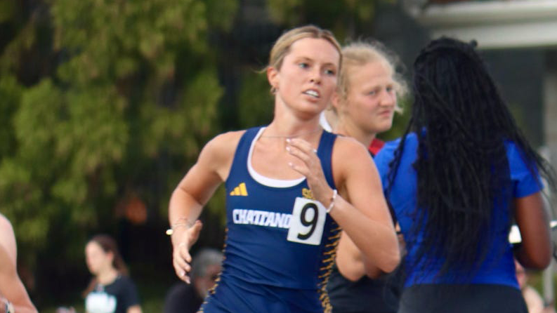 A close up photo of a collegiate student-athlete running on a track in a race.