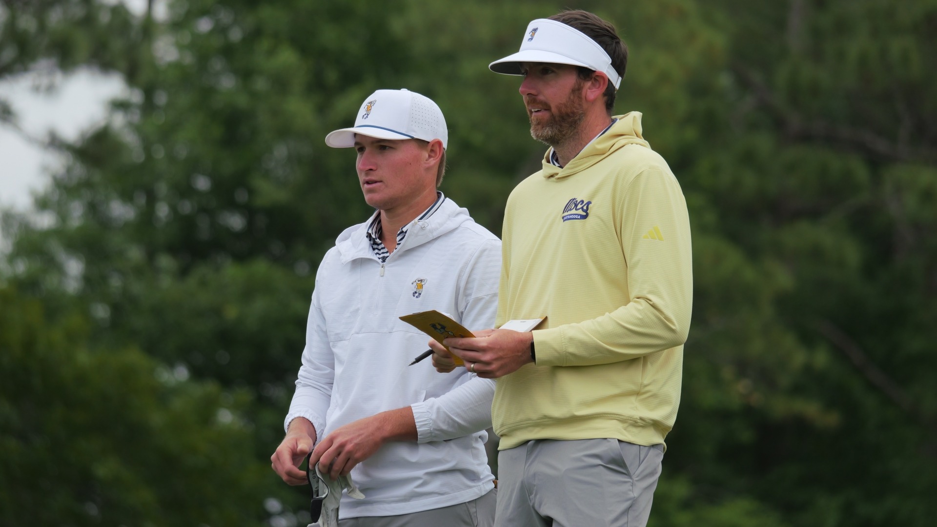 Coach Blaine Woodruff with yardage book in hand talks options with Griffin Law in the first fairway