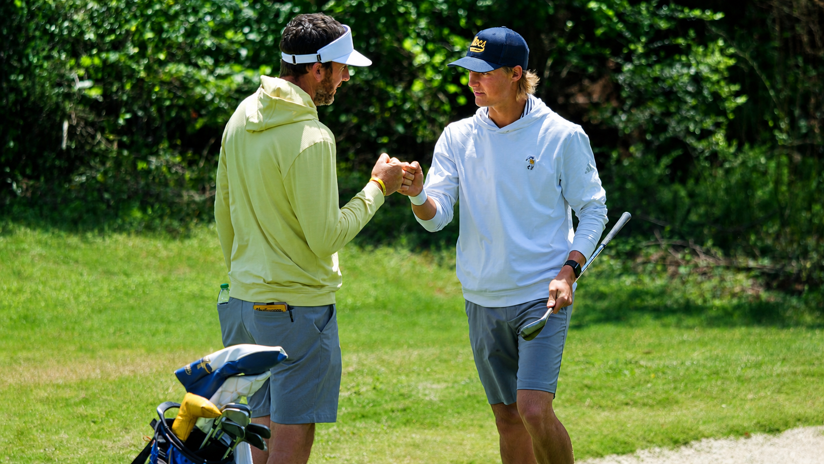 Evan Rogers and Blaine Woodruff fist bump in the fairway after a stellar shot at the SoCon Championships 