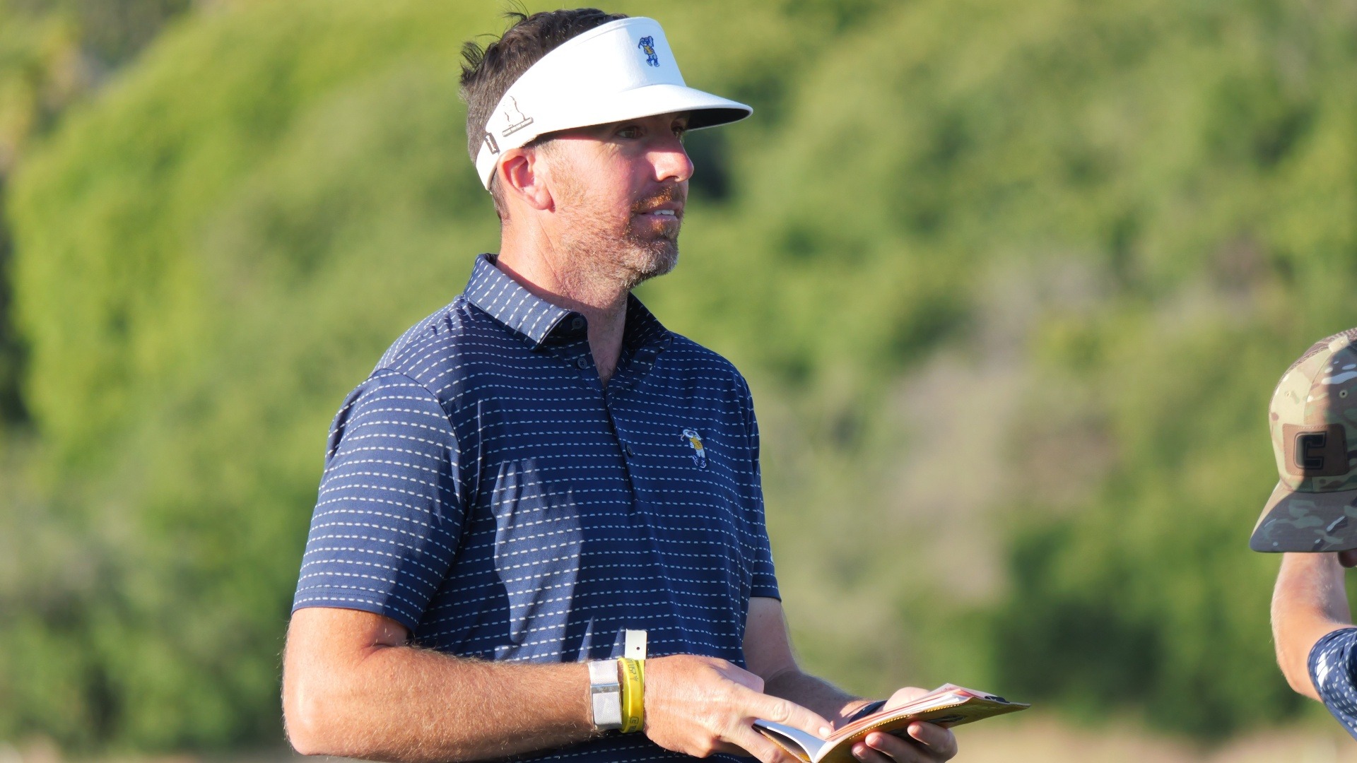 Coach Blaine Woodruff looks towards the green holding his open yardage book at the NCAA Championships.